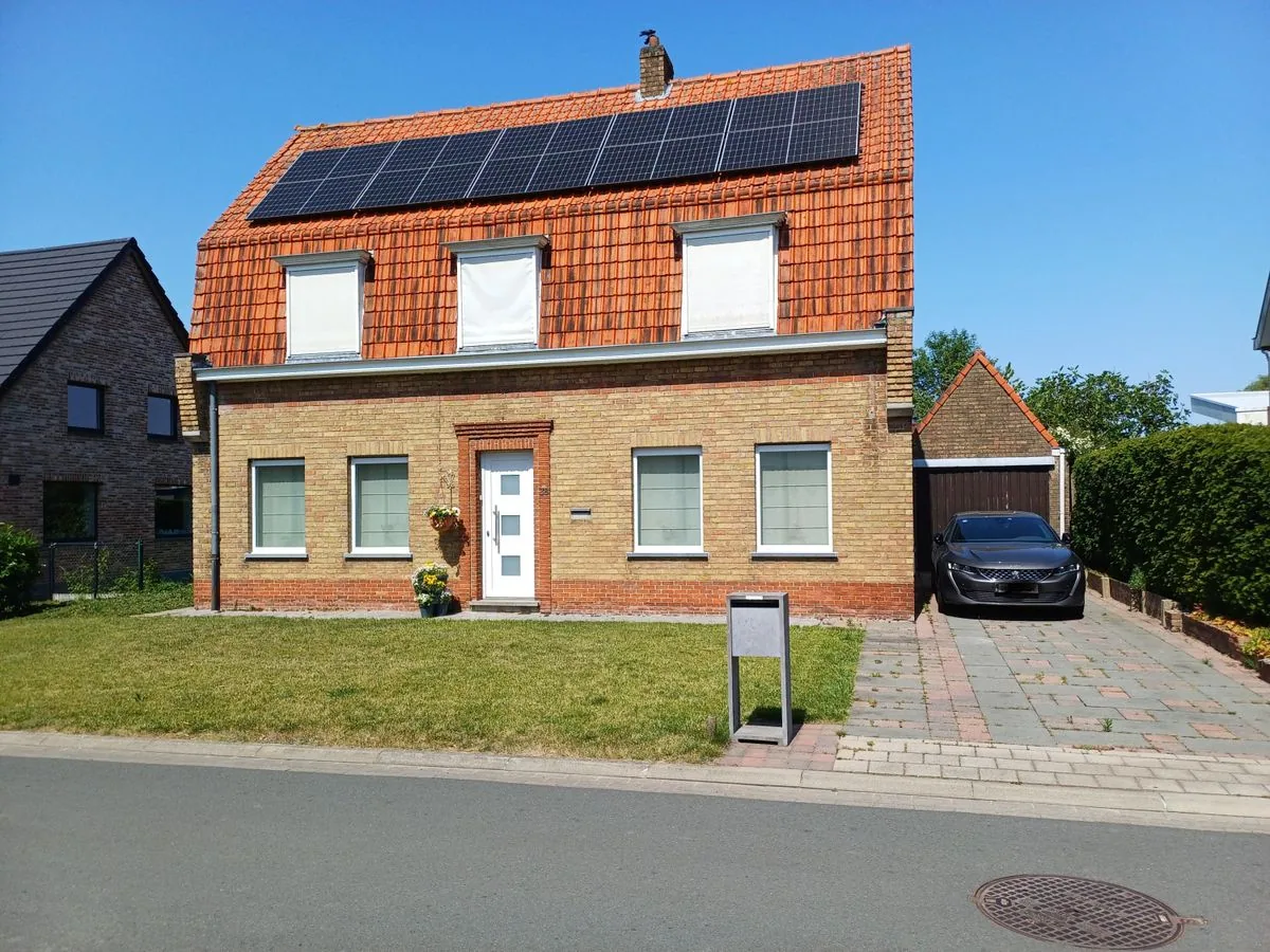 Voorgevel van de woning aan de Poelstraat 38 in Oostkamp, met oprit, garage en zonnepanelen op het dak