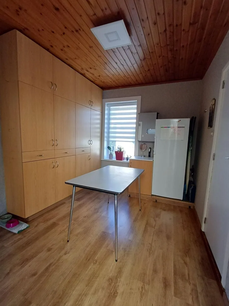 Bijkeuken met kasten, tafel en koelkast